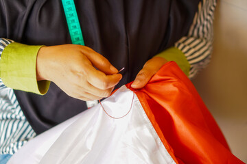 A woman sews the red and white flag, Indonesia's national flag. The theme is celebrating independence on August 17, 1945.