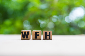 Wooden block arrangement forming the acronym WFH against nature background. Commonly used to...
