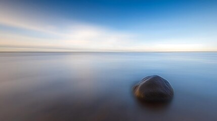 Minimalist seascape with distant rock structure, long exposure using neutral density filter, solitary rock softened by blurred ocean, pastel-toned sky above