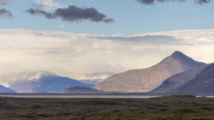 the view of storm clouds over snow covered mountain peaks in Southeastern Iceland near Vestrahorn, Iceland