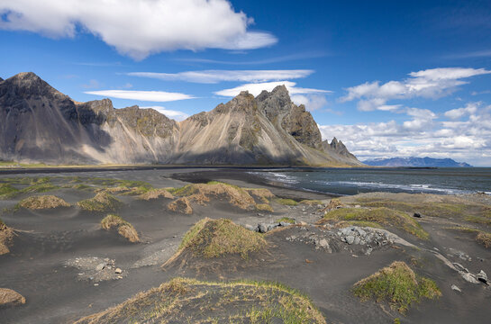 grassy dunes, black sand beach, Atlantic ocean and Vestrahorn mountain ridge in June, East Iceland