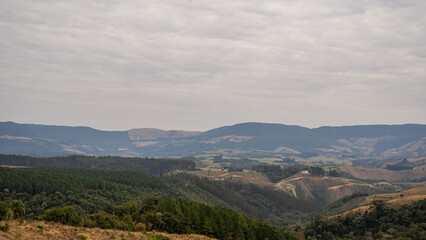 Golden sunset over the rolling green hills of a rural farm in Paraná, Brazil. A peaceful and serene countryside landscape with a rustic fence in the foreground
