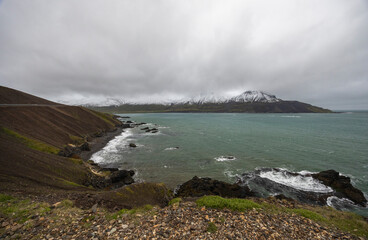 view of Icelandic fjord with snow covered mountains on a cloudy day,  Naddahjalli, Njarðvíkurskriður, East Iceland