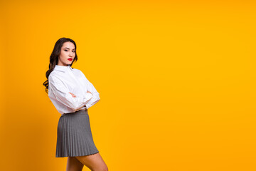 Confident young woman in formal attire posing against a vibrant yellow background, showcasing a...