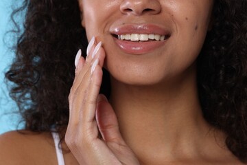 Smiling woman with glossy lip balm on her lips, closeup