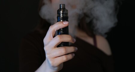 Woman using electronic smoking device on black background, closeup