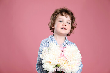 Cute little boy with bouquet of beautiful peonies on pink background. Space for text