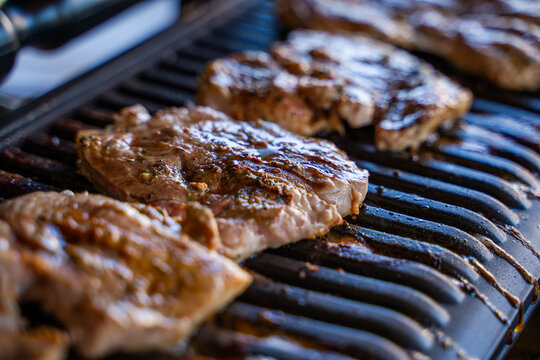Pork steak being grilled on an electric grill, close-up