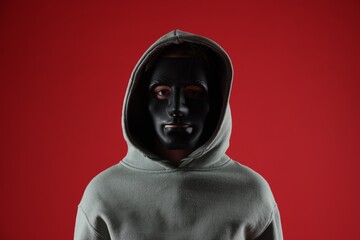 Anonymity. Woman wearing mask on red background