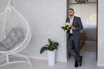 Stylish man with bouquet in modern home setting during daytime