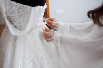 Woman adjusts intricate wedding dress in elegant preparation for special occasion