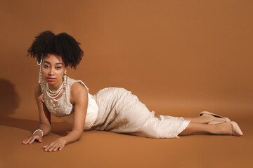 Fashionable portrait of beautiful Brazilian woman in stylish outfit on light brown background