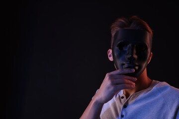 Anonymity. Man wearing mask on black background, space for text