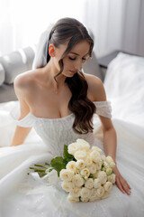 Elegant bride holding bouquet of white roses in serene bridal setting
