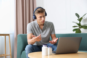 Man in headphones having online consultation with doctor via laptop at home