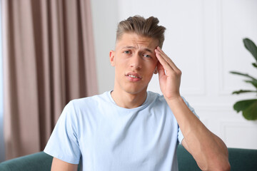 Sad man suffering from headache at home. Online medical consultation