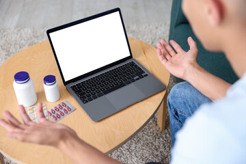 Man having online consultation with doctor via laptop at home, above view