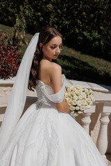 Elegant bride holding bouquet in a sunlit garden during wedding celebration