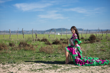 Young woman, pretty, brunette, flamenco dancer, barefoot, showing her beautiful dress, posing...