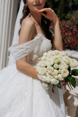 Beautiful bride in a sparkling gown holding a bouquet at an outdoor wedding venue