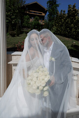 Couple celebrating their wedding day under a beautiful veil in a scenic outdoor setting