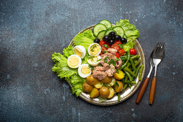 Classic French Nicoise salad with tuna, eggs, potatoes, green beans and olives on a silver platter...