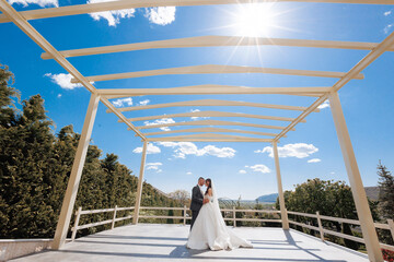 Couple celebrates wedding under bright sun at outdoor venue with elegant architecture