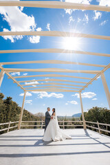 Couple exchanges vows under a clear blue sky at a wedding venue on a sunny day
