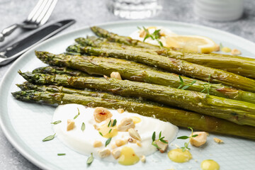Tasty cooked asparagus served with lemon and sauce on grey table, closeup