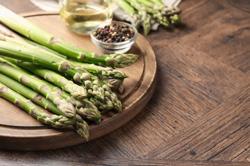 Fresh raw asparagus on wooden table, closeup. Space for text