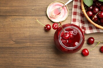 Tasty cherry jam and fresh fruits on wooden table, flat lay. Space for text