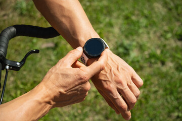 Athlete cyclist checking distance, pulse or fitness progress in apps after riding. Close up man...