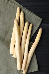 Raw white asparagus spears on black wooden table, flat lay