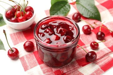 Tasty cherry jam and fresh fruits on white table, closeup
