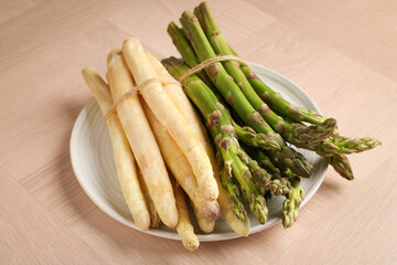 Different raw asparagus spears on wooden table, closeup