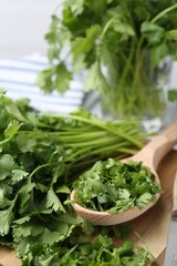 Naklejka premium Fresh green cilantro and wooden spoon on table, closeup