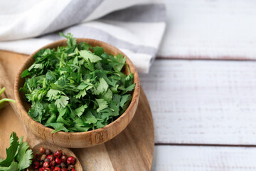 Fresh green cilantro and peppercorns on white wooden table, closeup. Space for text