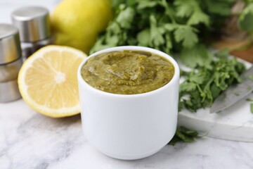 Tasty sauce with cilantro and other ingredients on white marble table, closeup
