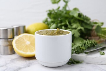 Tasty sauce with cilantro and other ingredients on white marble table, closeup