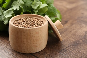 Fresh cilantro and coriander seeds on wooden table, closeup. Space for text
