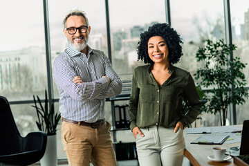 Confident business team of a male and female in a modern office space emphasizing professionalism...