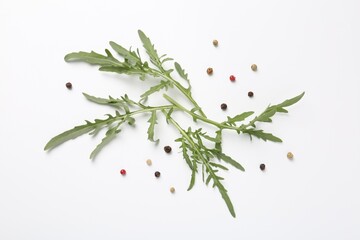 Fresh ripe green arugula leaves and peppercorns on white background, flat lay