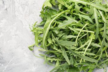 Fresh ripe green arugula leaves on grey table, top view. Space for text
