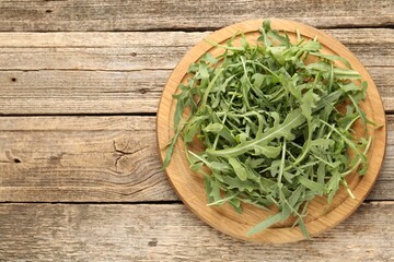 Fresh ripe green arugula leaves on wooden table, top view. Space for text