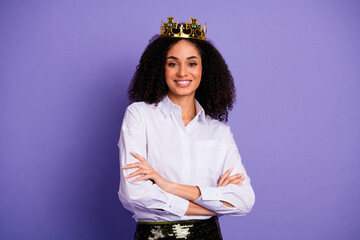 Confident woman wearing a crown and white shirt, exuding elegance and authority, standing against a...