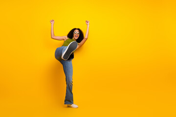 African American woman posing with enthusiasm and energy against a vivid yellow background in...