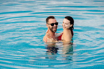 Young beautiful couple relaxing and enjoying vacation in the pool. Concept love, summer leisure,...
