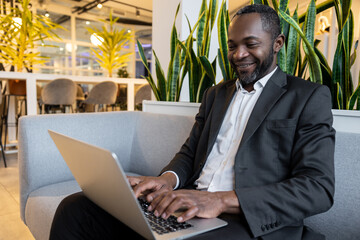 African american businessman working on a laptop and feeling contented and smiling