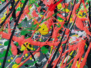 Abstract background of acrylic and latex construction paint. Green, red, yellow and black spots of flowing splashed paint. Abstract expressionism on a palette.