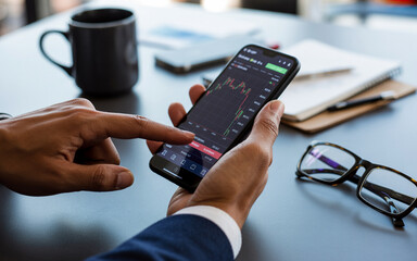 Investor examining stock market trends on a smartphone displaying financial data in a professional setting